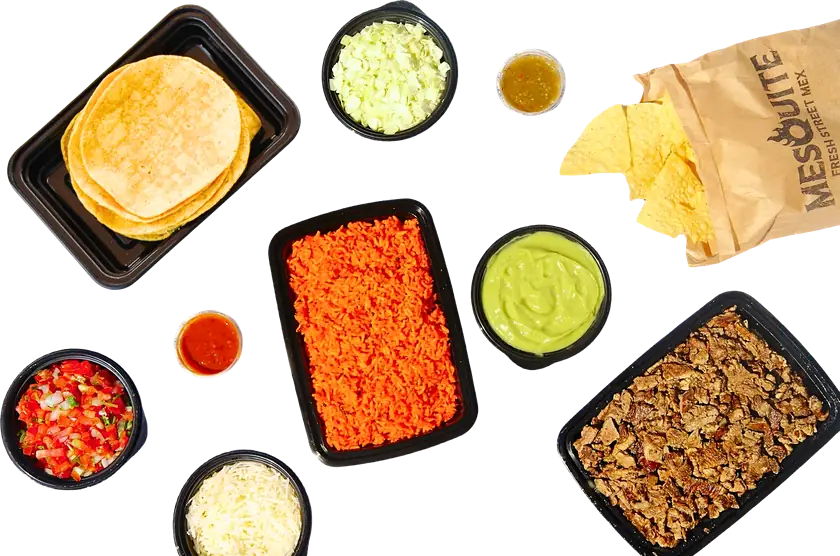 Mesquite Fresh Street Mex catering spread: trays of Spanish rice and grilled meat, tortillas, chips, guac sauce, pico de gallo, cheese, cabbage, and salsas