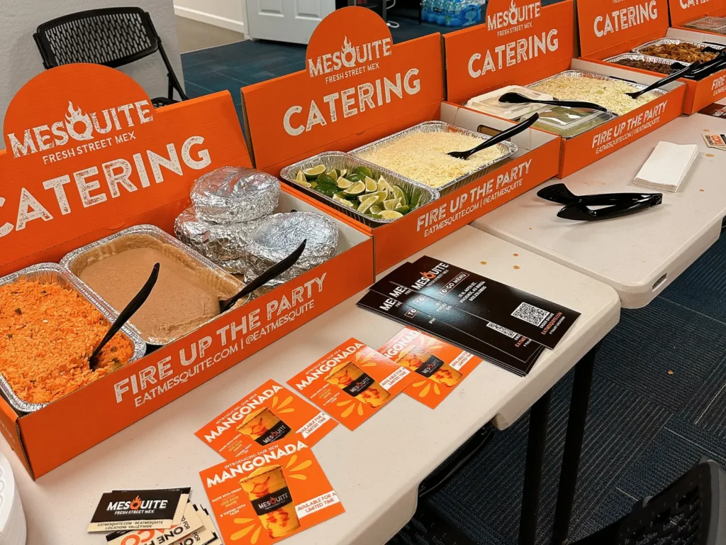 Mesquite taco bar catering set up on a long table with rice, beans, limes and toppings