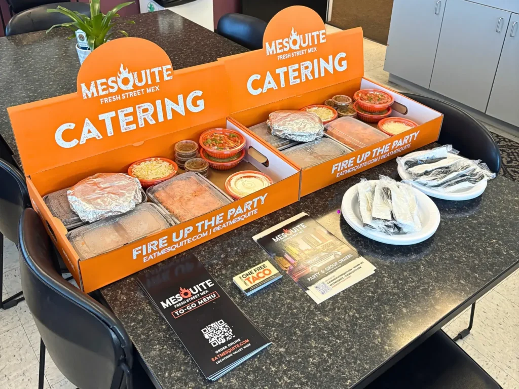 Mesquite taco bar catering boxes and breakfast burritos set up on an office conference table