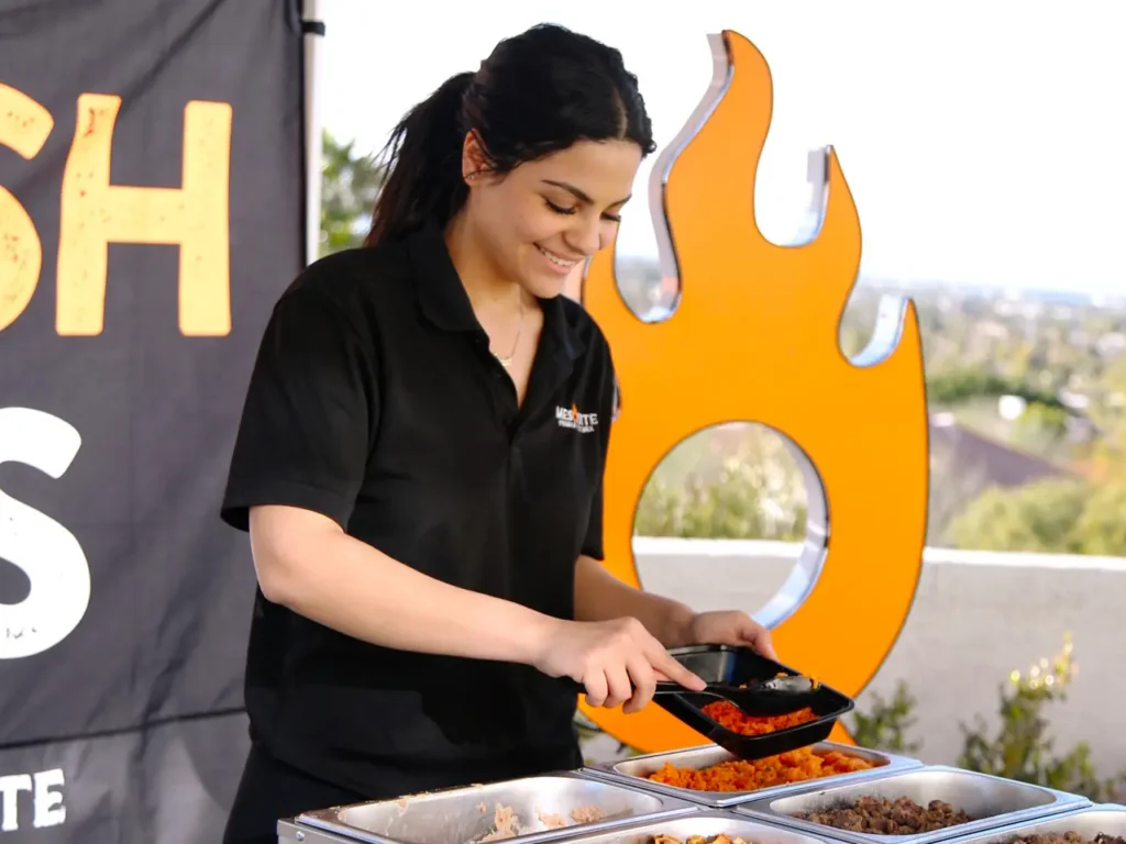 Mesquite team member serving fresh rice and grilled meats at an outdoor catering tent